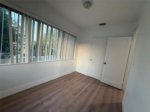 a view of an empty room with wooden floor and windows