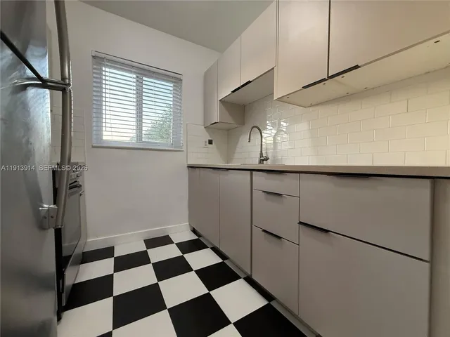 a kitchen with a checkered floor and white cabinets