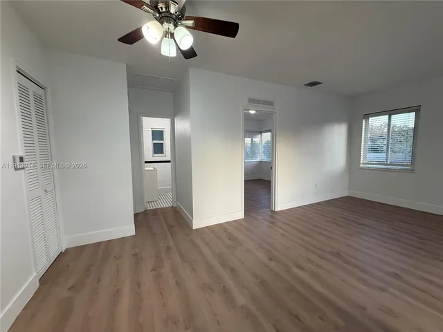 a view of an empty room with wooden floor and a window