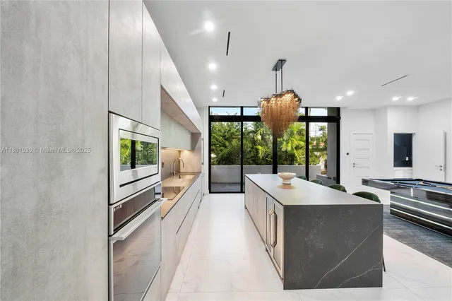 a dining hall with stainless steel appliances kitchen island granite countertop a stove and a chandelier