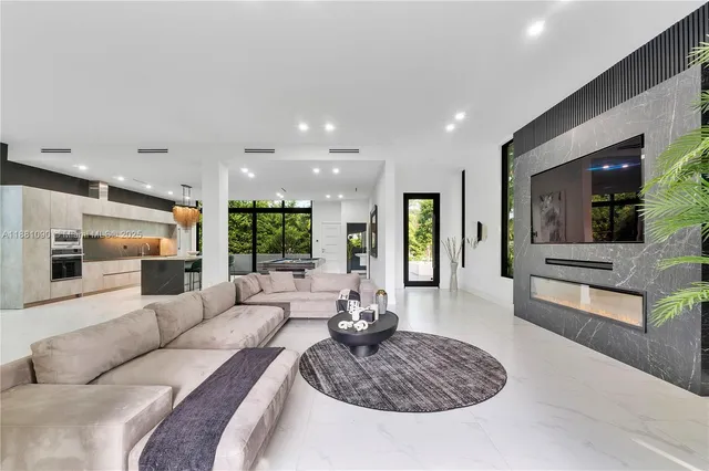 a living room with furniture kitchen view and a large window