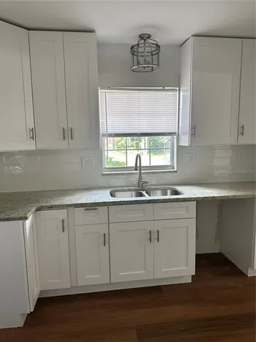 a kitchen with granite countertop white cabinets and a sink