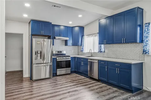 a kitchen with stainless steel appliances granite countertop a refrigerator stove a sink and dishwasher with wooden floor