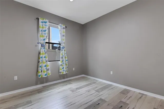 an empty room with wooden floor cabinet and windows