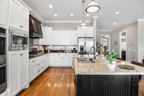 a kitchen with stainless steel appliances granite countertop a sink dishwasher stove refrigerator and cabinets