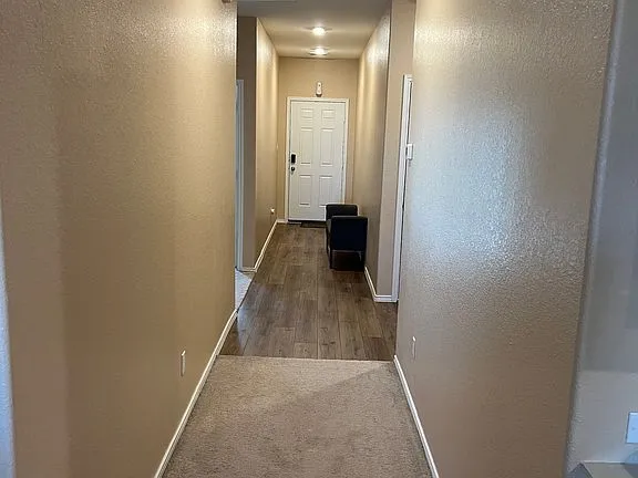 a view of a hallway with wooden floor and a bathroom