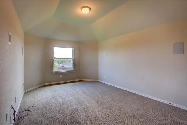 an empty room with kitchen view and wooden floor