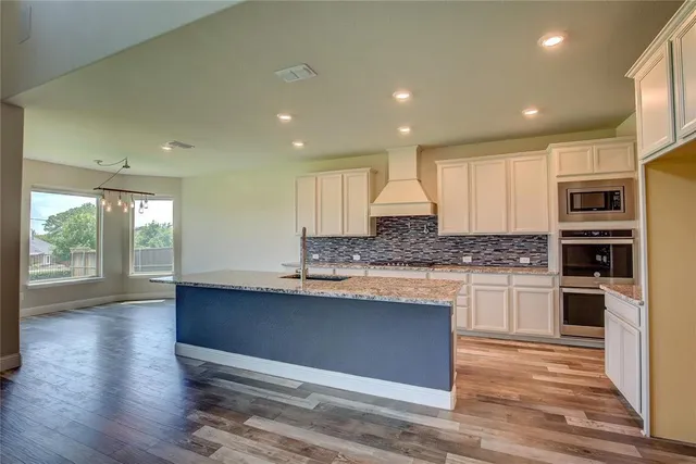 a kitchen with granite countertop a sink a stove and cabinets