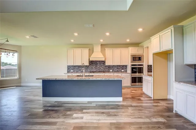 a kitchen with stainless steel appliances granite countertop a stove a sink and a refrigerator