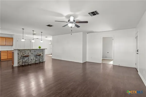 a view of an empty room with a kitchen and wooden floor