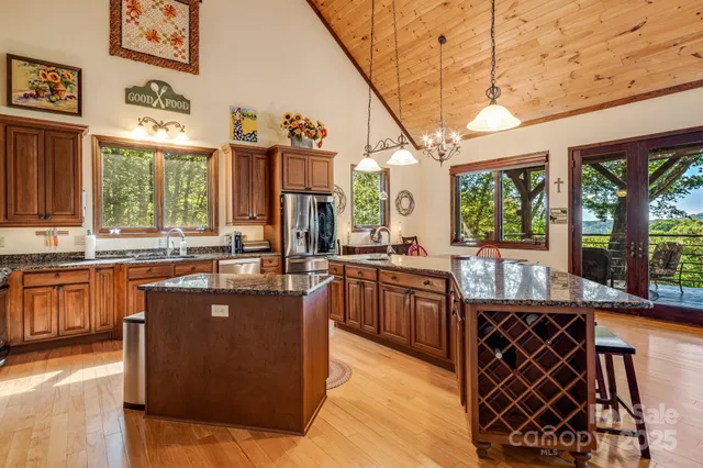 a large kitchen with stainless steel appliances granite countertop a stove and a view of living room