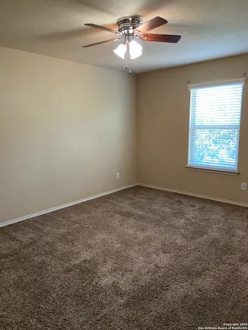 an empty room with windows and ceiling fan