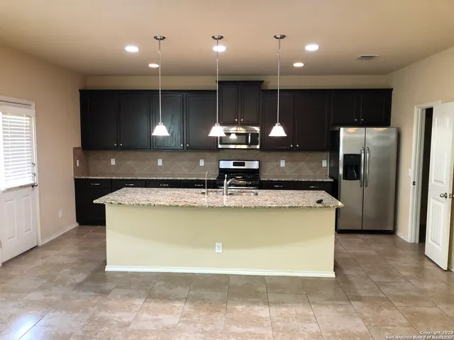 a large kitchen with stainless steel appliances kitchen island a large counter top a refrigerator and a sink