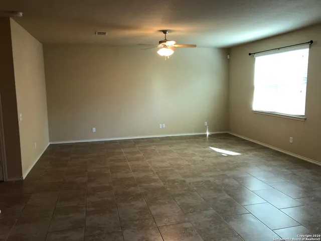 an empty room with a chandelier fan and windows
