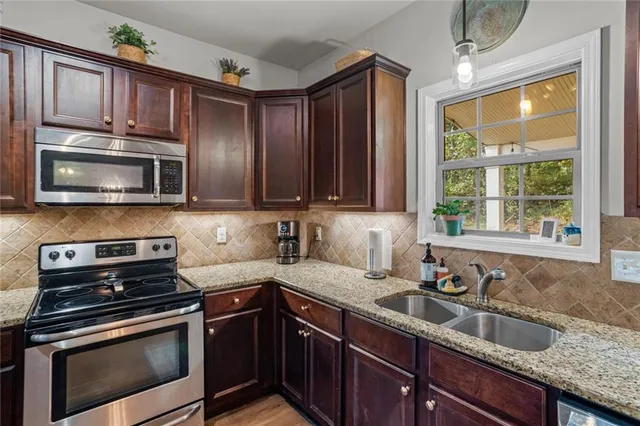 a kitchen with granite countertop wooden cabinets stainless steel appliances a window and a sink