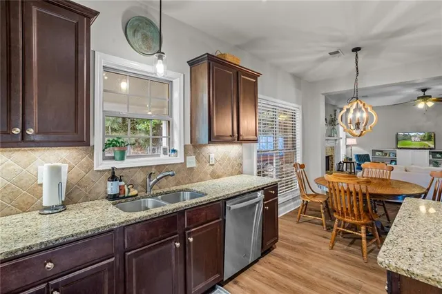 a kitchen with granite countertop wooden cabinets a sink a window and stainless steel appliances