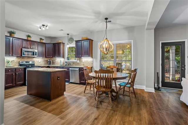 a kitchen with stainless steel appliances granite countertop wooden floors stove and dining table