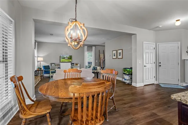 a dining room with wooden floor a chandelier a wooden table and chairs