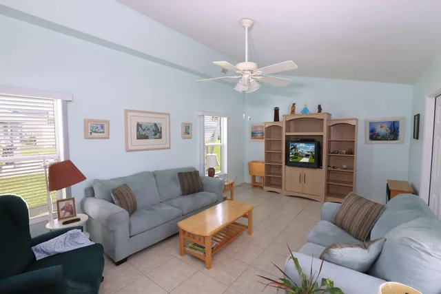 a living room with furniture a ceiling fan a lamp and a window