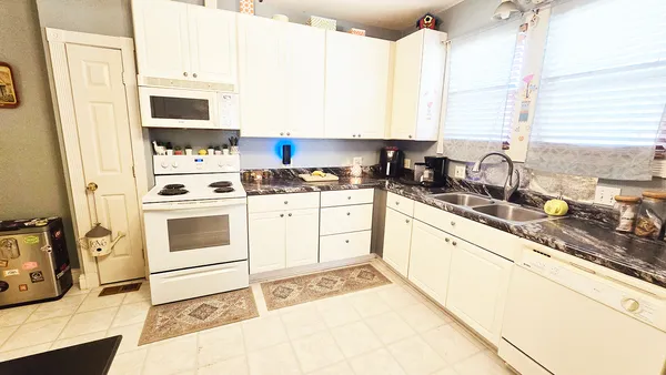 a kitchen with stainless steel appliances kitchen island granite countertop a sink a stove a microwave a counter space and cabinets