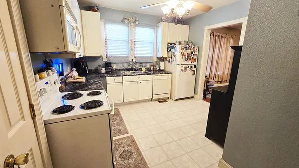 a kitchen with a refrigerator a stove a sink dishwasher and white cabinets with wooden floor
