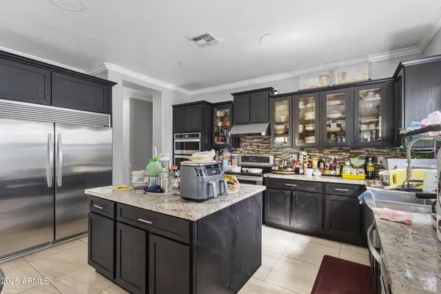 a kitchen with stainless steel appliances granite countertop a refrigerator a stove and a sink with wooden cabinets