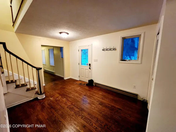 a view of an empty room with wooden floor and stairs