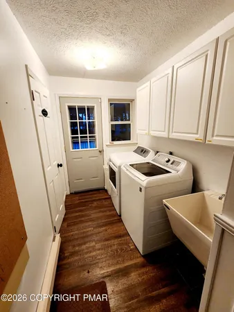 a utility room with wooden floor washer and dryer