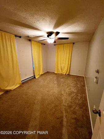 an empty room with a ceiling fan and window