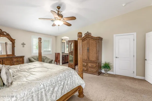 a spacious bedroom with a bed a dresser and a chandelier