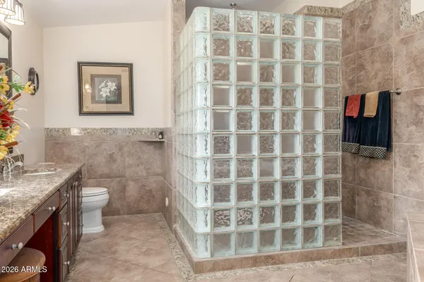 a bathroom with a granite countertop toilet a sink and a mirror