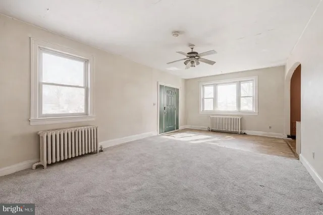 an empty room with windows and ceiling fan