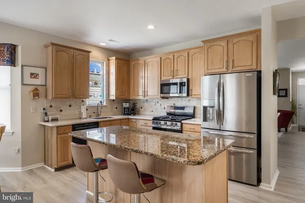 a kitchen with stainless steel appliances granite countertop a refrigerator a stove a sink a dining table and chairs
