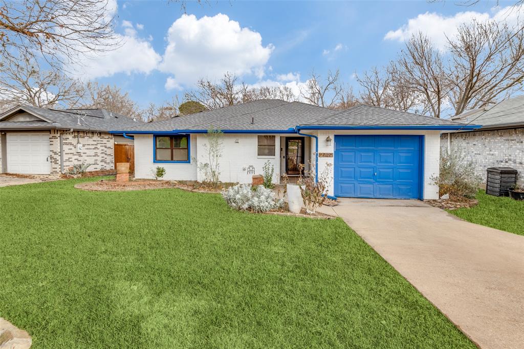 Ranch-style home featuring roof mounted Solar Panels, front lawn, attached garage, and brick siding