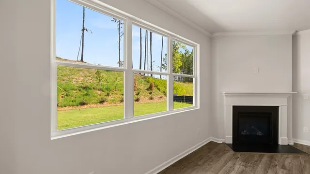 a view of an empty room with a window and wooden floor
