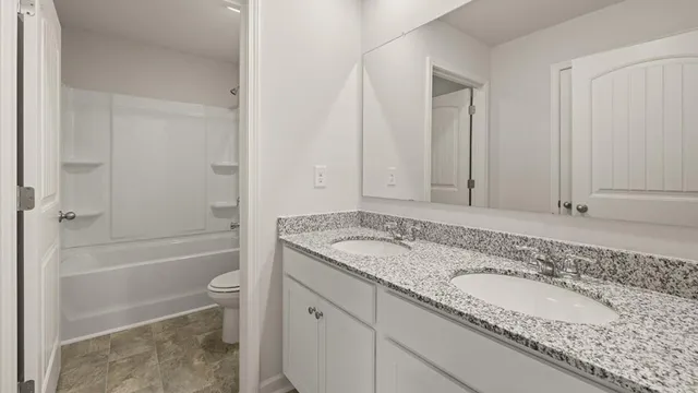 a bathroom with a granite countertop sink a toilet and bathtub