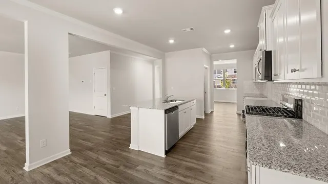 a large white kitchen with wooden floor and stainless steel appliances