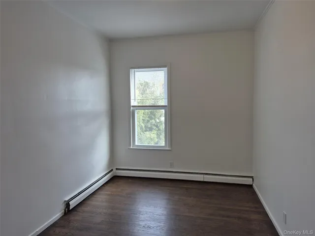 an empty room with wooden floor and window