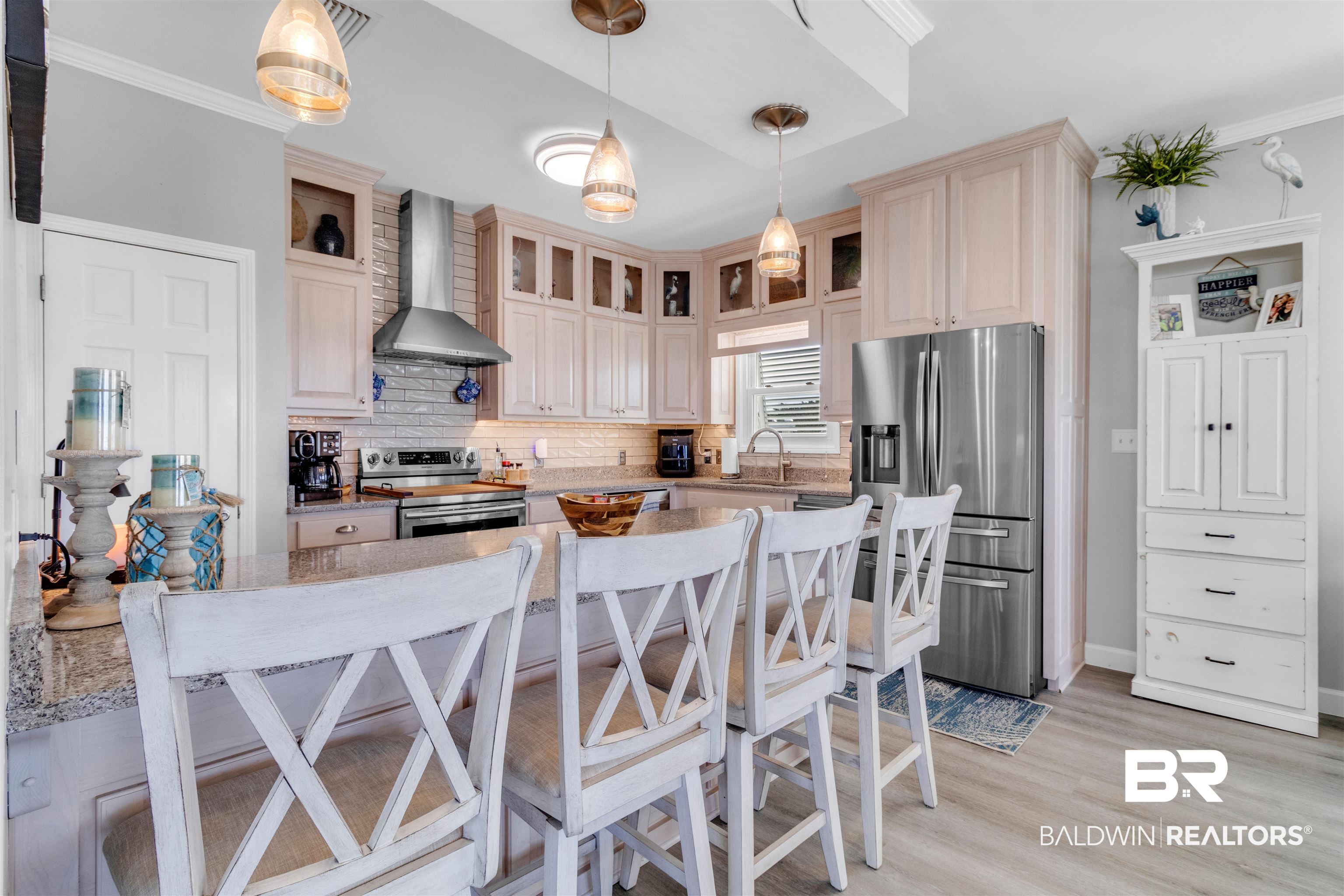 418 Veterans Road Gulf Shores, AL 36542 - Photo 33 of 51 Kitchen with appliances with stainless steel finishes, wall chimney range hood, decorative light fixtures, light wood finished floors, and a kitchen bar