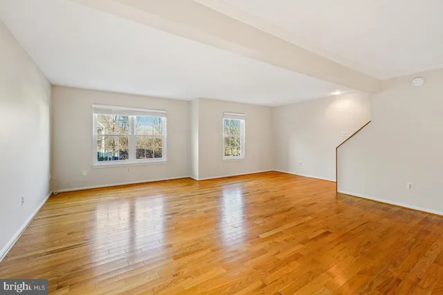 a view of an empty room with window and wooden floor