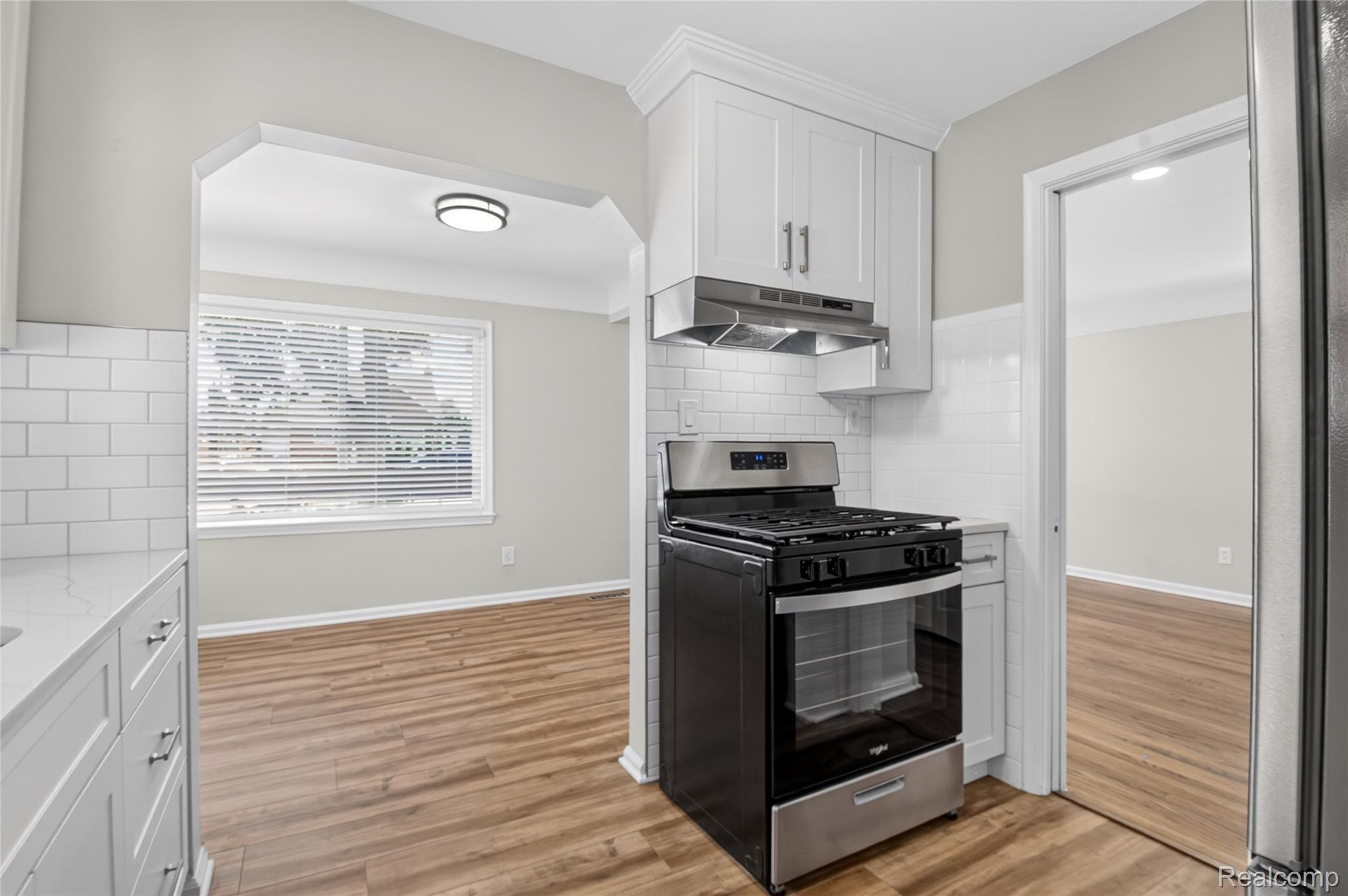 12972 Callender Street Southgate, MI 48195 - Photo 16 of 40 Kitchen featuring white shaker cabinetry, stainless steel range with overhead hood, subway tile backsplash, and wood-finish flooring