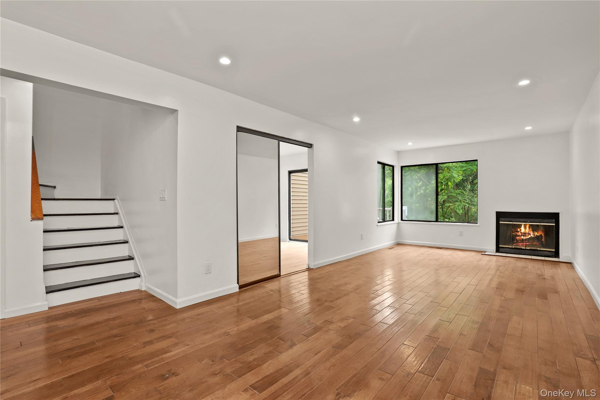 41 Rambling Brook Road Chappaqua, NY 10514 - Photo 8 of 29 Unfurnished living room with light wood-style floors, a glass covered fireplace, stairs, recessed lighting, and baseboards