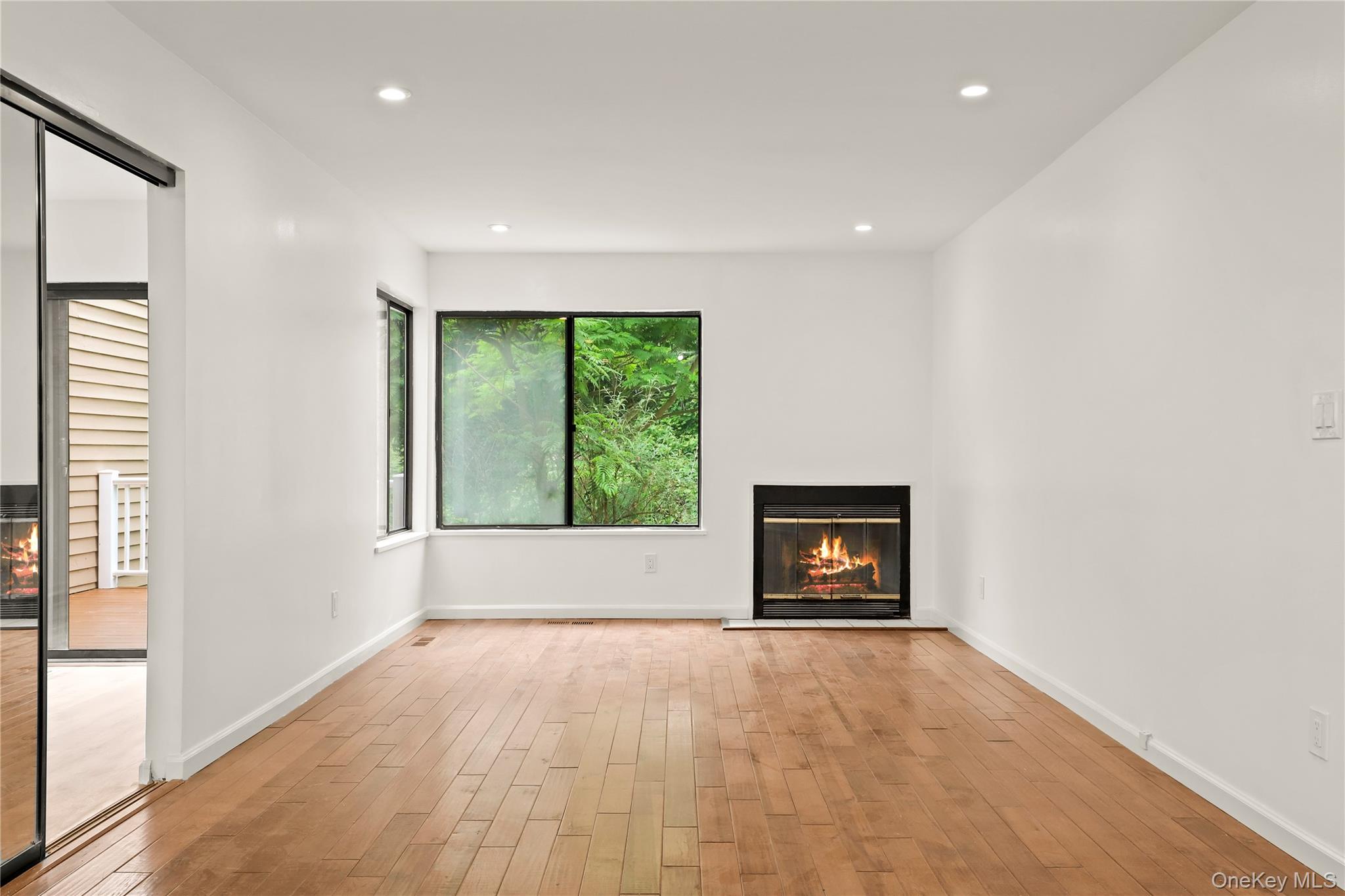 41 Rambling Brook Road Chappaqua, NY 10514 - Photo 9 of 29 Unfurnished living room featuring light wood-type flooring, a glass covered fireplace, recessed lighting, and baseboards