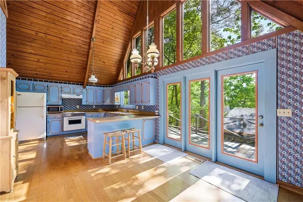 a kitchen with stainless steel appliances granite countertop a refrigerator a sink dishwasher a stove and white countertops with wooden floor