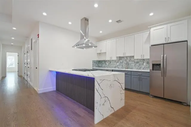 a large kitchen with stainless steel appliances kitchen island granite countertop a stove a sink and a refrigerator