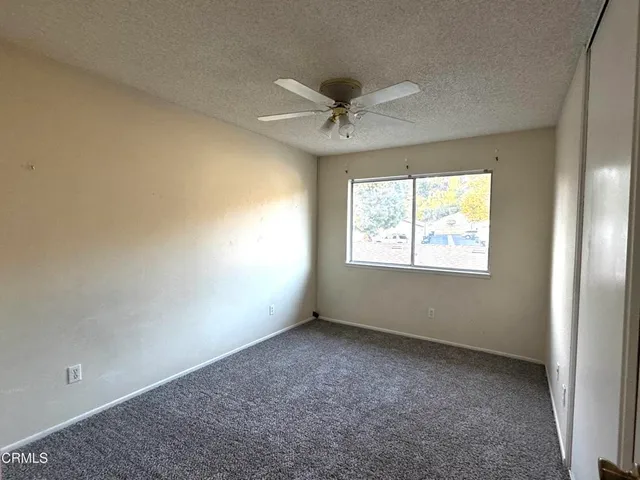 an empty room with a window and a fan