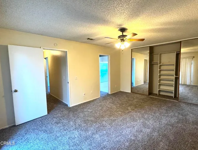 an empty room with closet and a chandelier fan