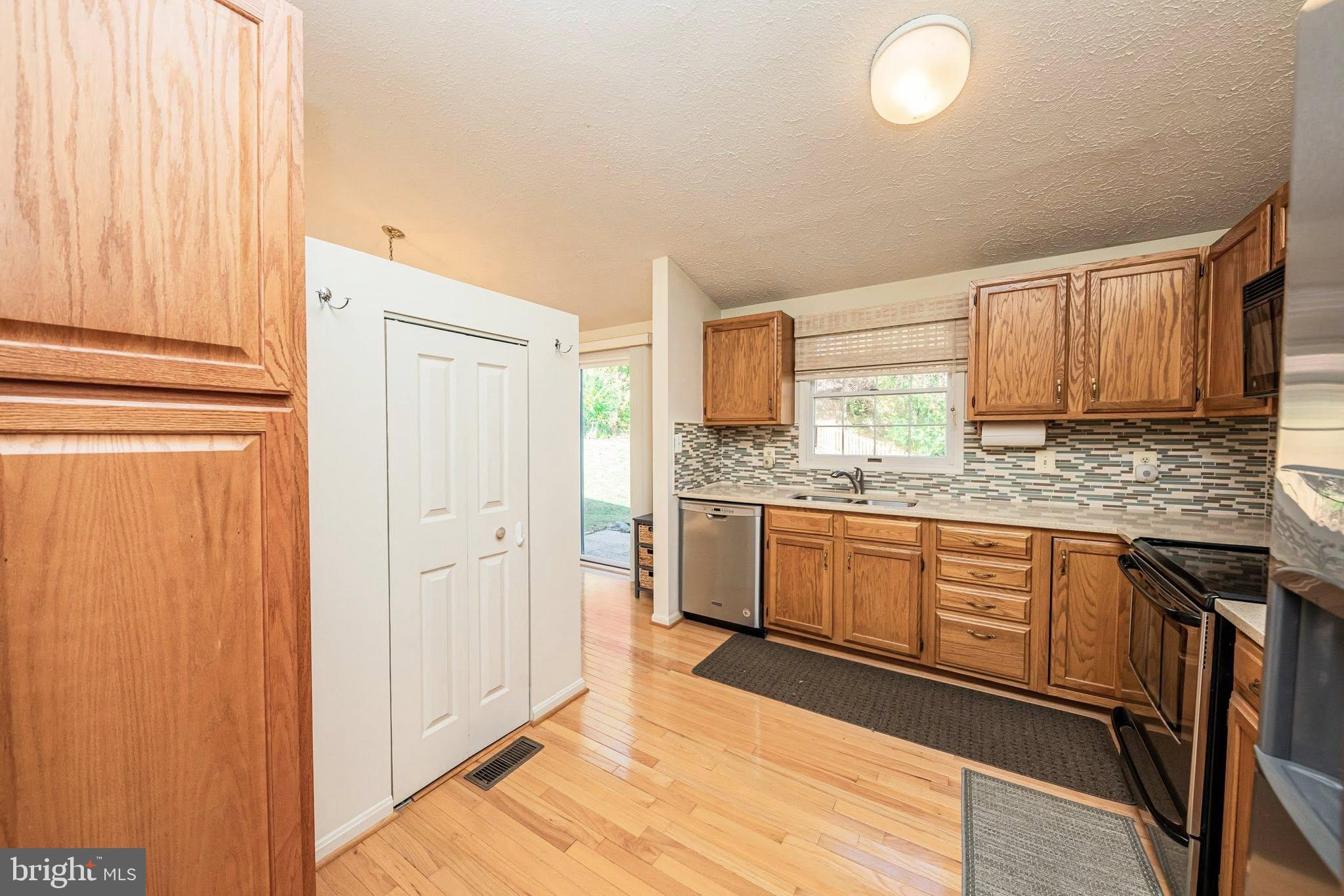1803 East Beech Road Sterling, VA 20164 - Photo 11 of 38 a kitchen with stainless steel appliances granite countertop a refrigerator a sink dishwasher and wooden cabinets with wooden floor