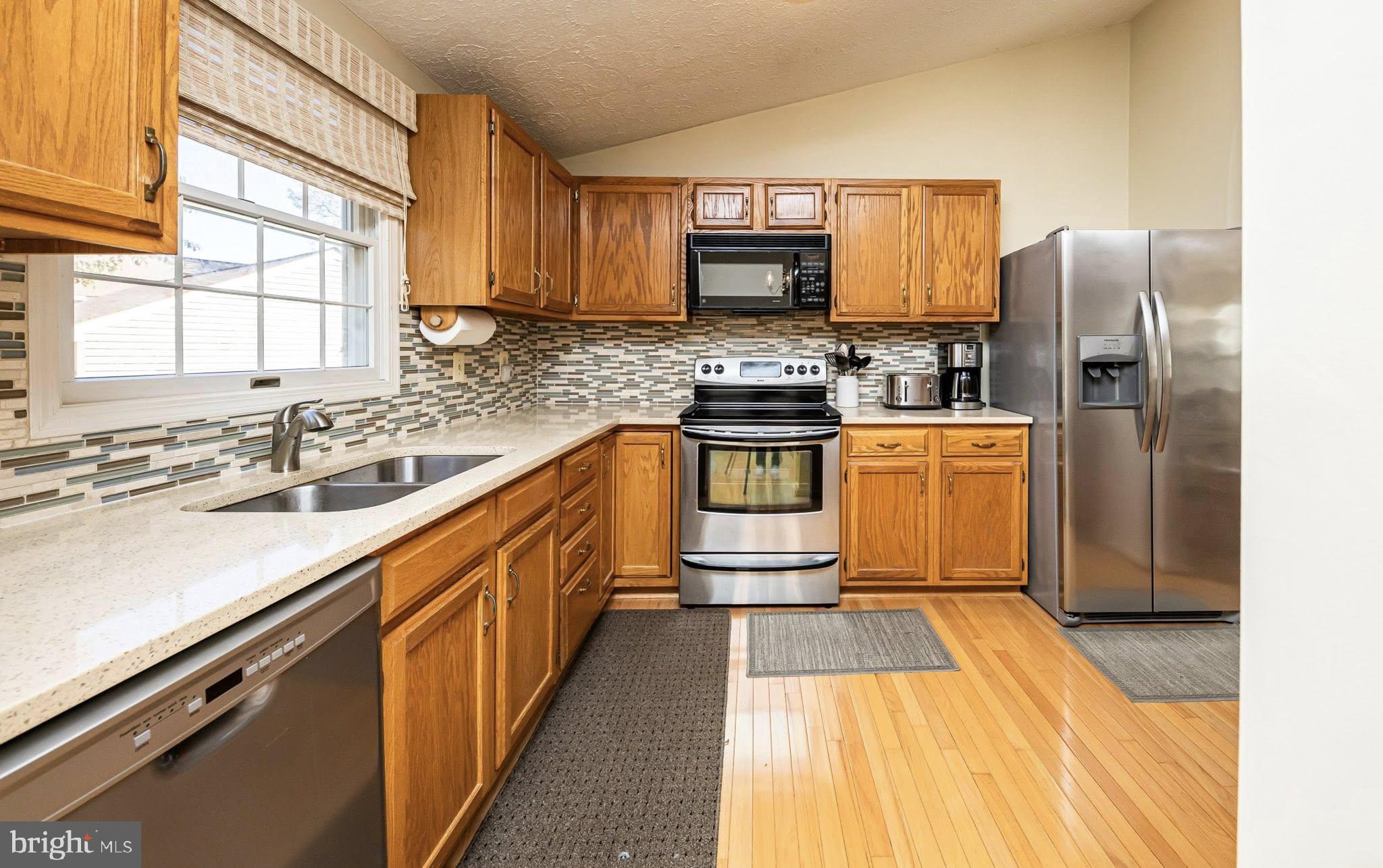 1803 East Beech Road Sterling, VA 20164 - Photo 9 of 38 a kitchen with stainless steel appliances granite countertop a sink stove microwave and refrigerator