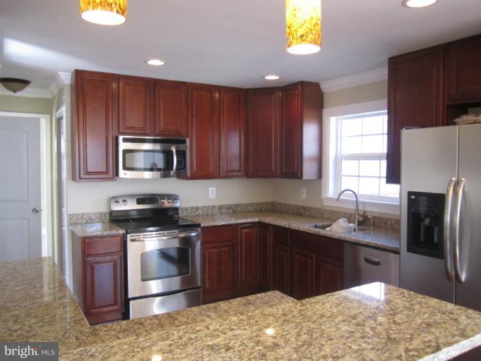 2107 Rolling Rd. Windsor Mill, MD 21244 - Photo 8 of 29 a kitchen with stainless steel appliances granite countertop wooden cabinets a stove top oven a sink and dishwasher